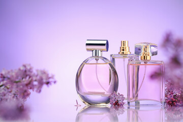 Bottles of perfume and lilac flowers on mirror surface against violet gradient background,...