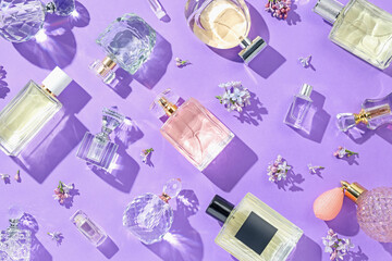 Flat lay composition with perfume bottles and lilac flowers on violet background