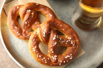 Tasty pretzels and beer on wooden table, top view