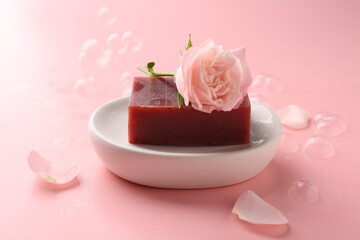 Soap bar and beautiful rose on pink background, closeup