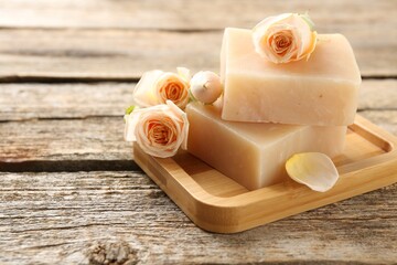 Soap bars and beautiful roses on wooden table, closeup. Space for text