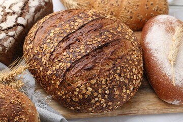 Fresh bread loaves and spikes on white table, closeup