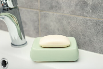 Soap bar near faucet on sink in bathroom, closeup