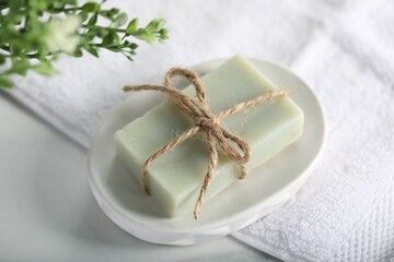 Soap bar, towel and floral decor on white table, above view