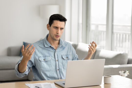 Technical breakdown. Angry irritated millennial man remote worker entrepreneur look on notebook screen dealing with system error slow internet connection stressed with technical issues data loss fail