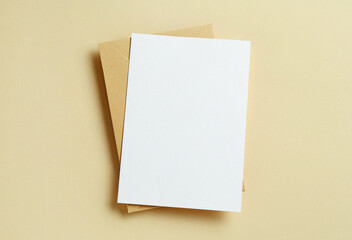 Blank invitation card and envelope on beige background, top view. Space for design