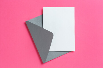 Blank invitation card and envelope on pink background, top view. Space for design