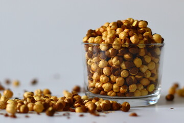 Crispy Roasted Channa chickpeas in a glass, scattered on white background