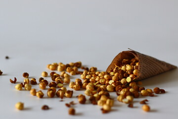 Crispy Roasted Channa chickpeas in a newspaper cone, scattered on white background.