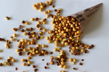 Crispy Roasted Channa chickpeas in a newspaper cone, scattered on white background.