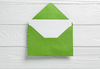 Blank invitation card and envelope on white wooden table, top view