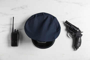 Police cap, gun and walkie talkie on white marble table, flat lay