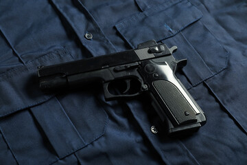 Black gun on dark blue uniform, above view. Police equipment