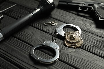 Different police equipment on black wooden table, closeup
