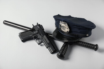 Police cap, gun and baton on white background