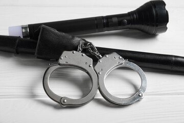Flashlights and handcuffs on white wooden table, closeup. Police equipment