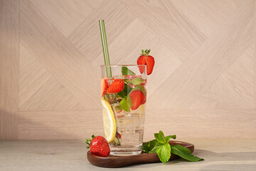 Tasty refreshing drink with strawberries, lemon and mint on wooden table