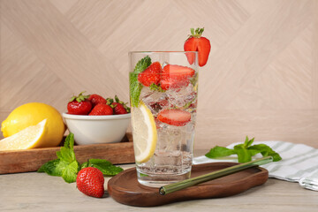 Tasty refreshing drink with strawberries, lemon and mint on wooden table