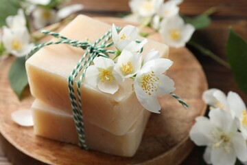 Soap bars and jasmine flowers on wooden table, closeup