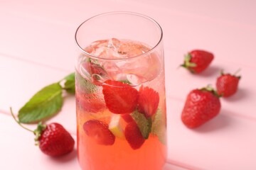 Refreshing drink with strawberries, mint and ice on pink wooden table, closeup