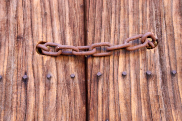 Cadena metálica oxidada sobre puerta de madera 
