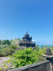 Coastal Temple Shrine: A serene coastal temple, perched atop a verdant hill, stands majestically against a brilliant blue sky.