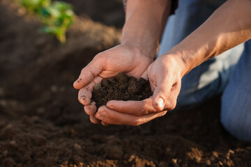 Man holding pile of soil in field, closeup
