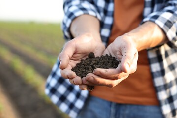 Man holding pile of soil in field, closeup