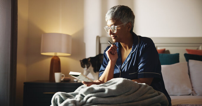 Thinking, crossword and book with old woman in bed for puzzle, strategy game and reading. Brainstorming, problem solving and solution with senior person in bedroom of home for relax and idea