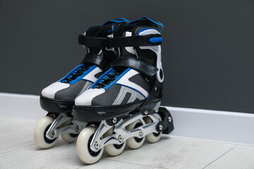 Pair of roller skates on floor near black wall, space for text