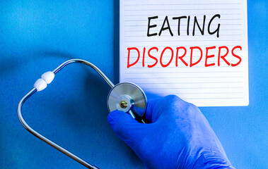 Eating disorders symbol. Concept words Eating disorders on beautiful white note. Doctor's hand in...