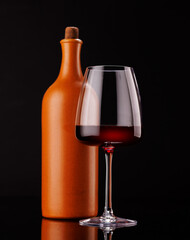 Elegant presentation of red wine in a glass and a bottle against a dark background