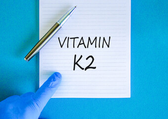Vitamin K2 phylloquinone symbol. Concept words Vitamin K2 on beautiful note. Doctor's hand in blue...
