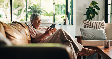 Mature woman, phone and couch in home with reading, texting and notification. Person, thinking and...