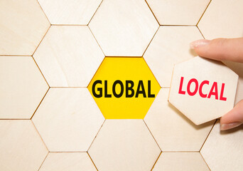 Global and Local symbol. Concept word Global and Local on wooden comb puzzle. Businessman hand....