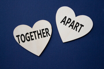 Together or Apart symbol. Concept word Together or Apart on wooden hearts. Beautiful deep blue...