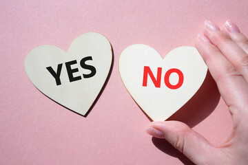 Yes or No symbol. Concept word Yes or No on wooden hearts. Businessman hand. Beautiful pink...