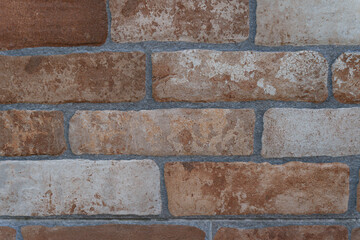 Close-up view of a weathered brick wall highlighting texture, color variations, and the effects of...