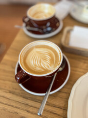  Fresh cappuccino in brown ceramic cup on wooden café table