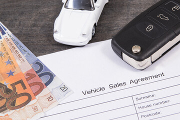 White toy car, car key, euro banknotes and vehicle sales agreement. Sales, purchases of automobile. Transportation