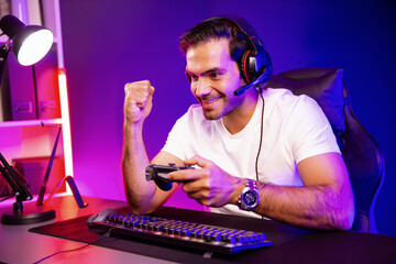 Winner smart streamer playing online game with joystick wearing headphones raising fist up on...