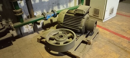 old Soviet equipment.  Old Soviet electric motor with belt on wooden pallet in industrial setting  