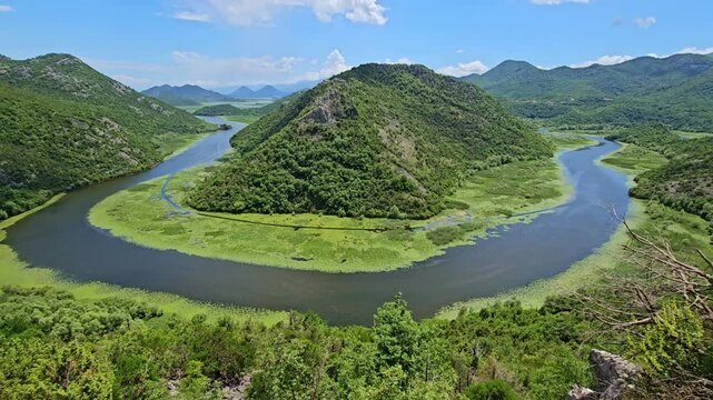 panning of Breathtaking view of rijeka crnojevica winding through a vibrant green valley in skadar lake national park, montenegro