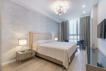 A bright and airy bedroom featuring a comfortable bed, stylish lighting fixtures, and contemporary...