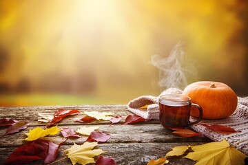 Warm autumn scene with pumpkins and coffee cup on a rustic wooden table surrounded by colorful leaves in the glow of sunset