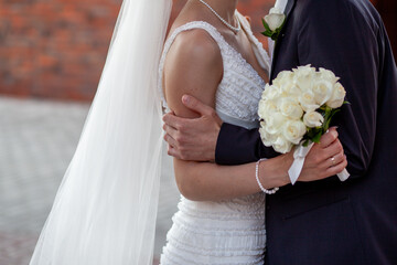 Bride and groom embrace holding white bouquet