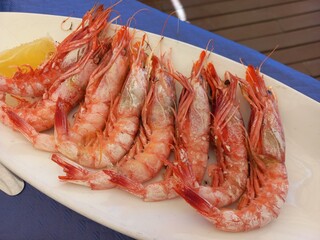 Grilled shrimps with lemon on white plate for summer dining experience. Mediterranean food