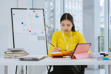 Focused Asian Woman Studying with Tablet and Notebook