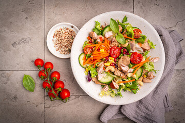 Salad with chicken meat on gray background, top view. Fresh vegetable salad with chicken. Meat salad with chicken fillet and fresh vegetables on plate. High quality photo