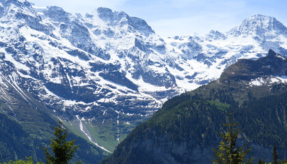 Majestic snow-capped peaks rise above lush green valleys, showcasing the breathtaking beauty of the...